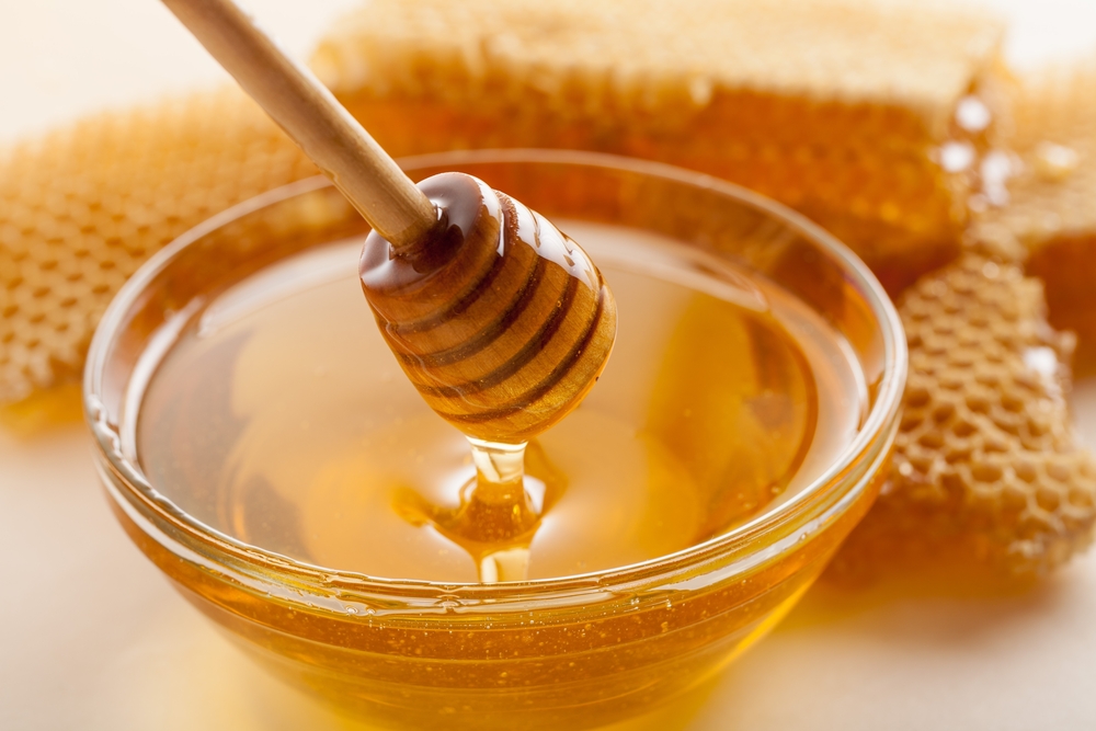 A bowl of honey next to honeycomb.