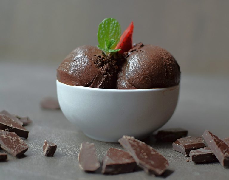 Chocolate sorbet in a bowl with mint and a strawberry.