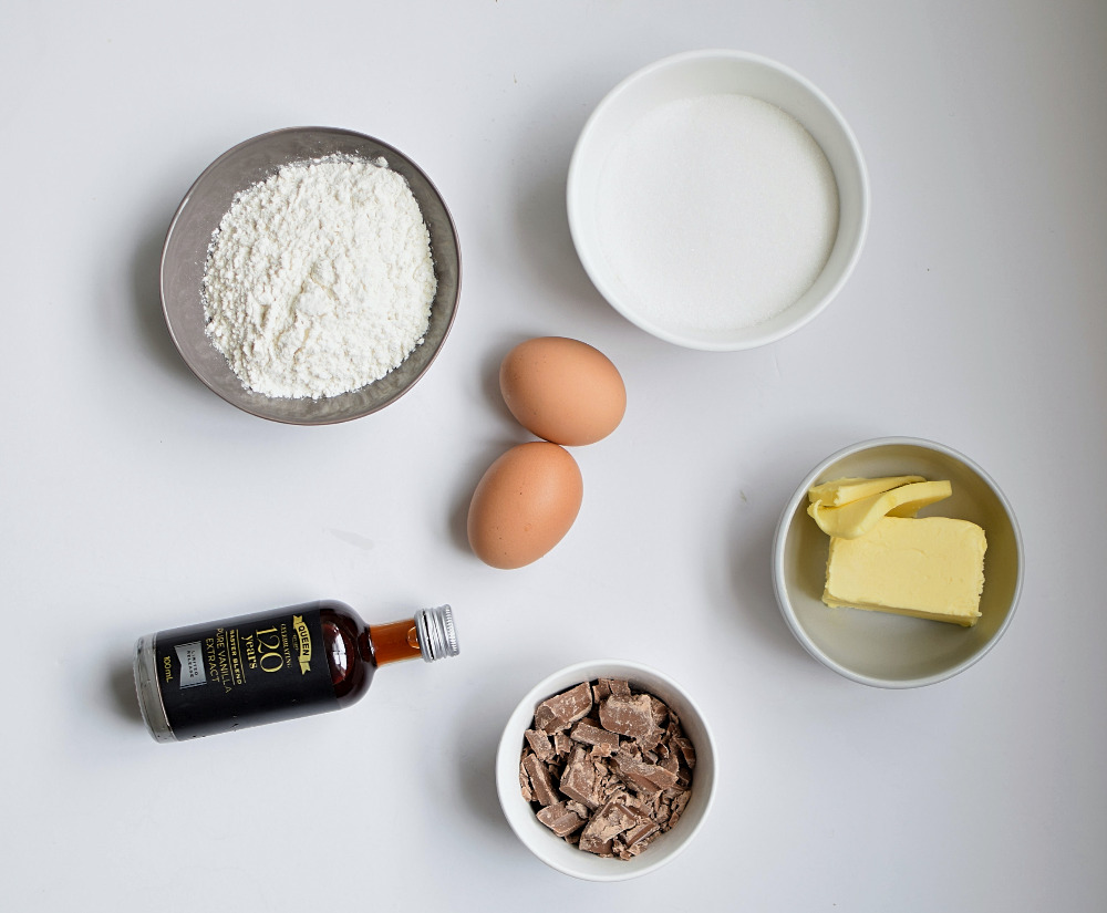 Ingredients to make blondies: flour, sugar, eggs, butter, vanilla and milk chocolate.