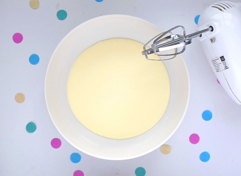 A bowl of cream with a beater next to it