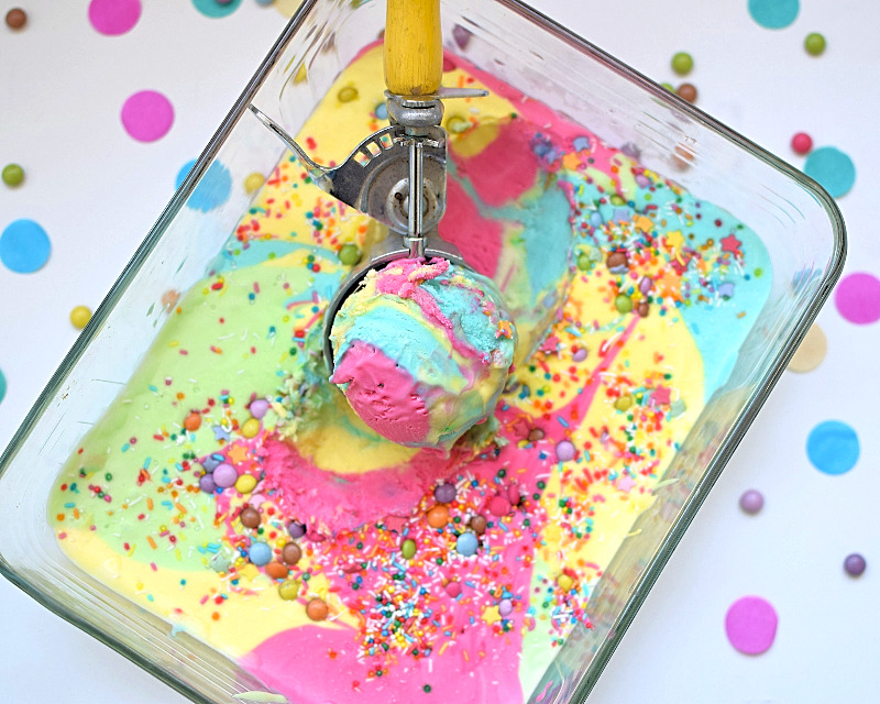 Super colourful rainbow ice cream in a dish with a scoop