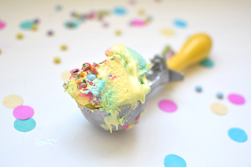 A scoop of rainbow ice cream on bench