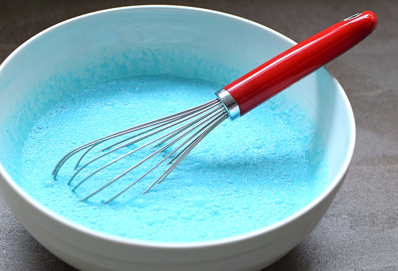 Ingredients in a large white bowl being whisked.