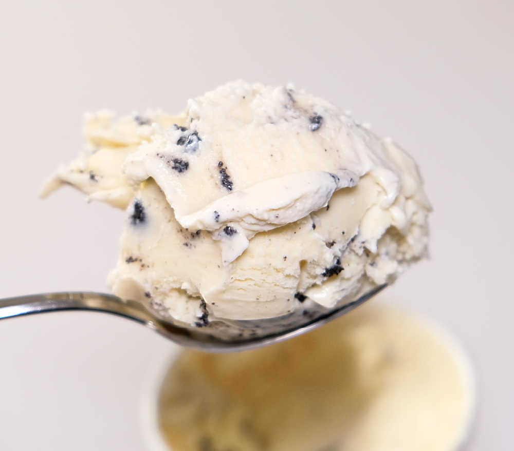 A spoonful of ice cream with the tub in the background.