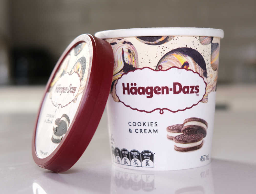 An opened tub of HD Cookies & Cream with the lid leaning against the side.