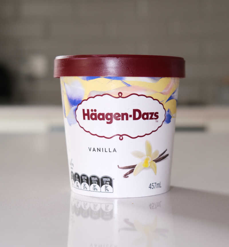 A vertical photograph of the Haagen-Dazs vanilla ice cream tub on a countertop.