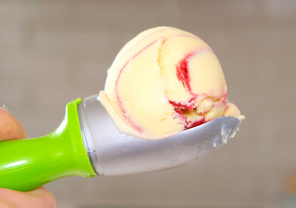 An isolated photograph of a scoop full of Mango Raspberry swirl ice cream.