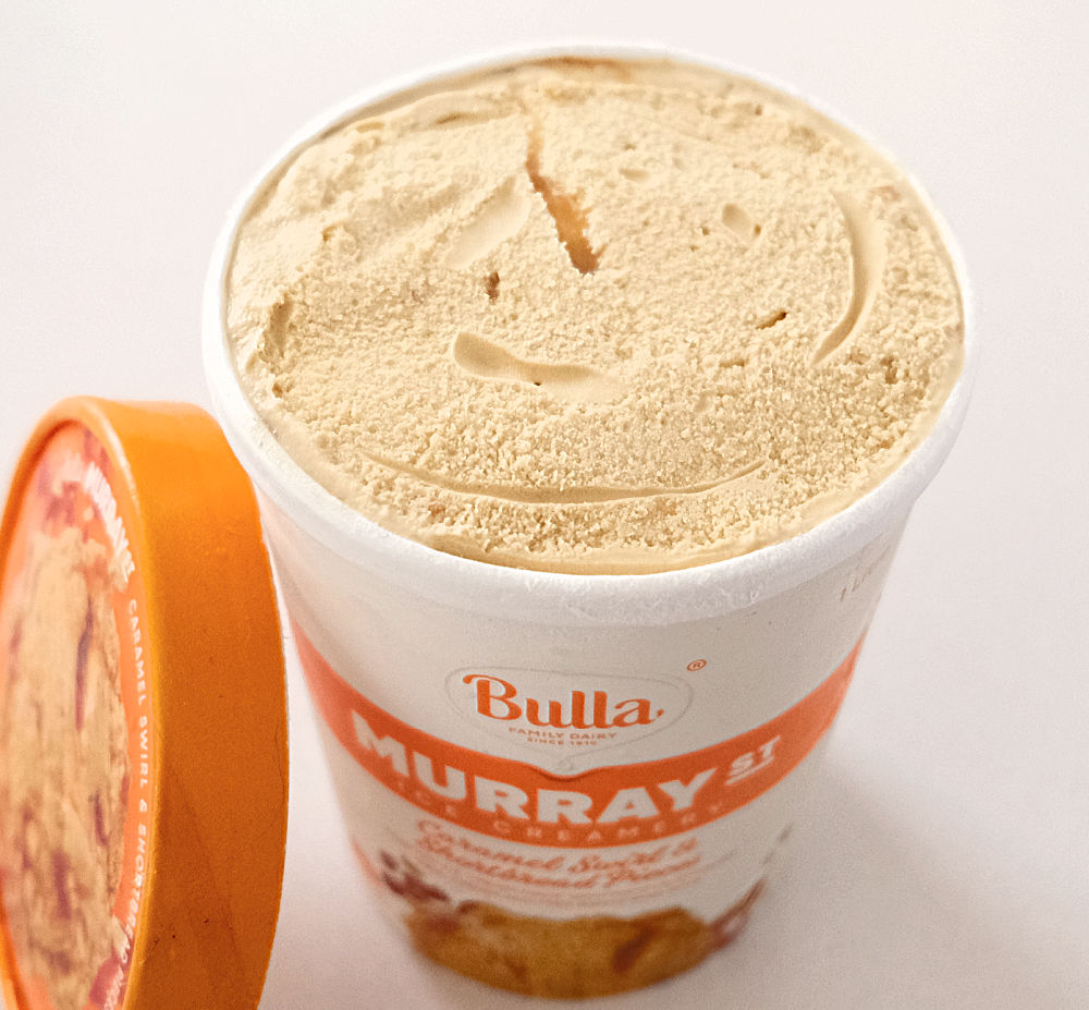 Macro image of a container of Murray St Caramel Ice Cream with the lid leaning against the side.