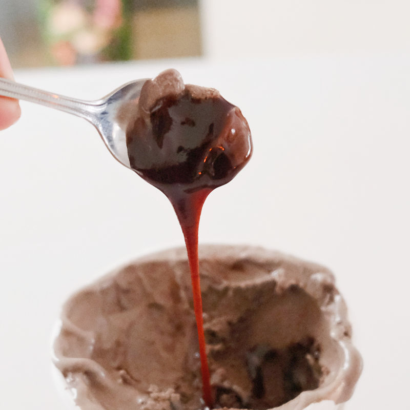 A photograph of a spoon pouring the chocolate ripple to demonstrate its runny consistency.