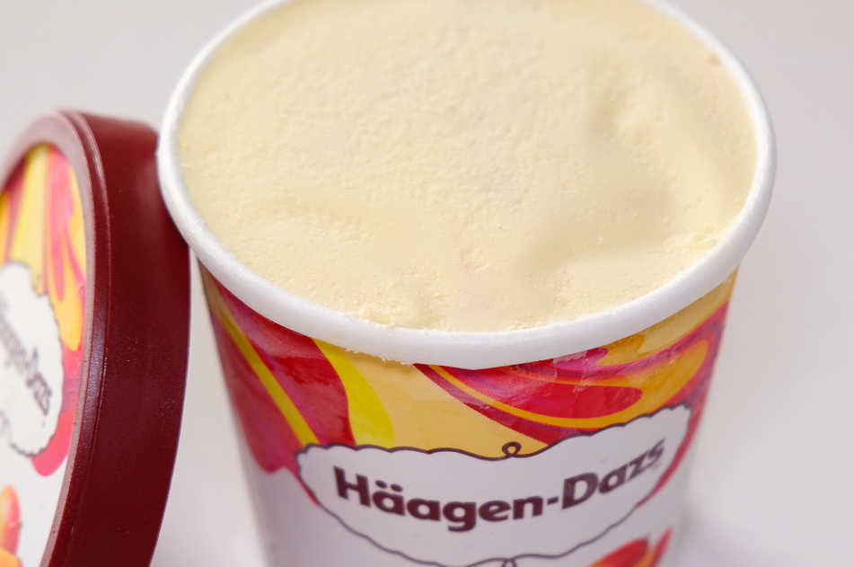 An opened tub of Haagen-Dazs Mango and Raspberry ice cream. The lid is leaning against the side of the container.