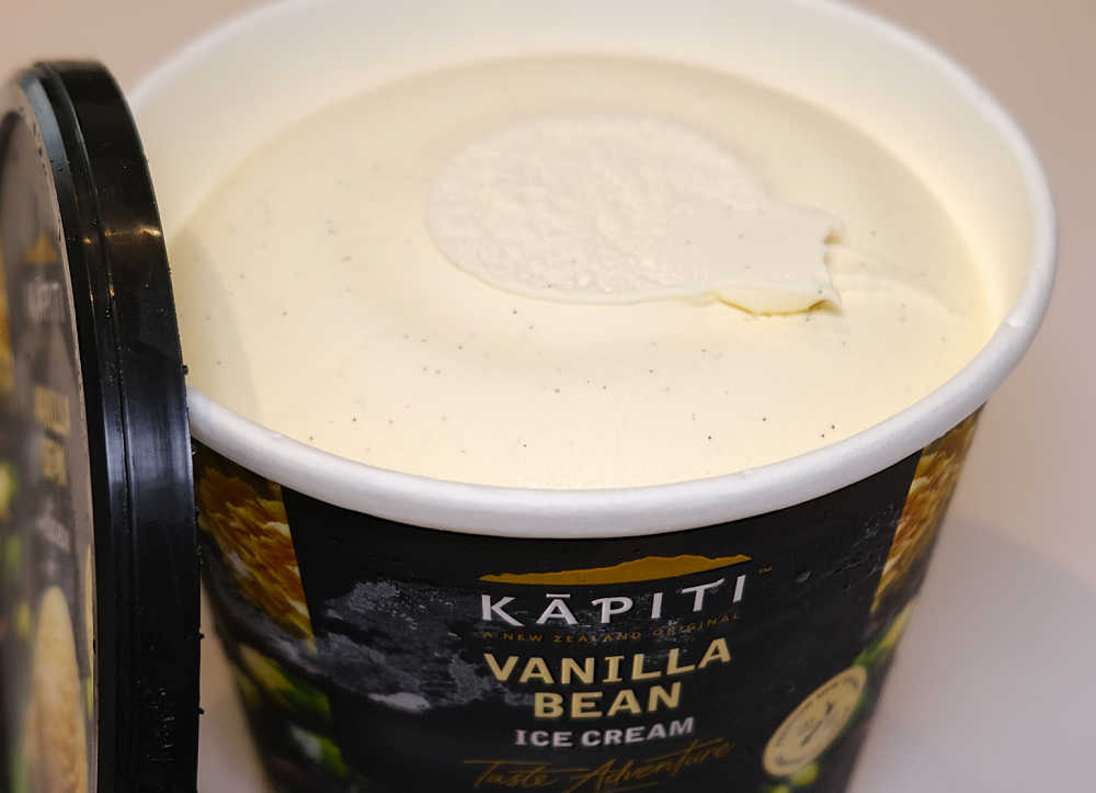 A shot of an open tub of Kapiti Vanilla Bean Ice Cream with the lid resting against the side.