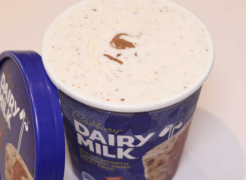 An unscooped container of Dairy Milk with the lid removed and resting on the side.