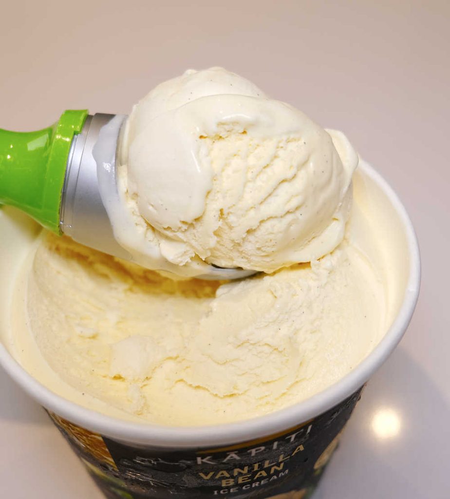 A scoop of Kapiti Vanilla Bean resting on the top of the tub.
