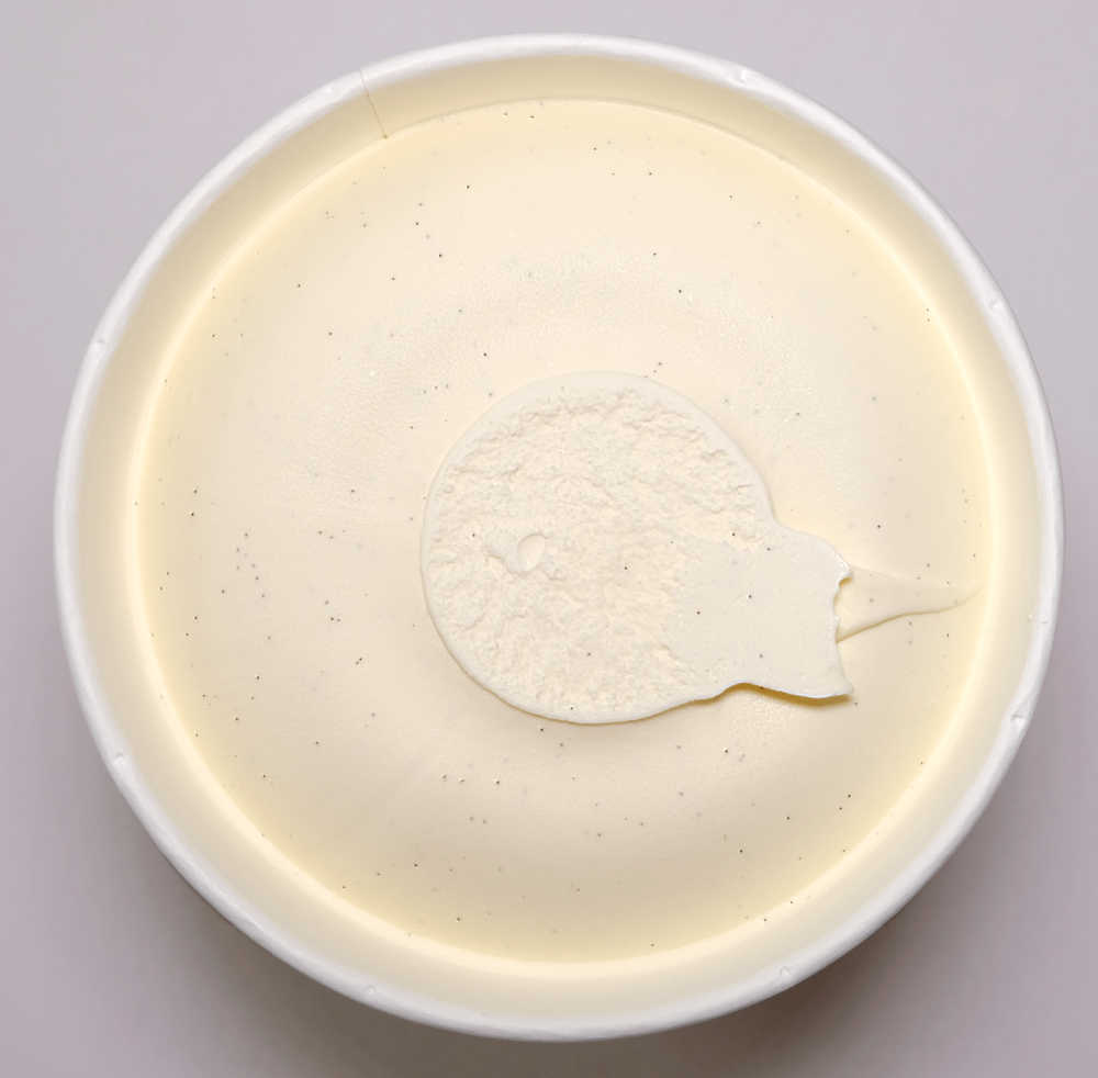 Top down pic of unscooped vanilla bean ice cream in a tub.