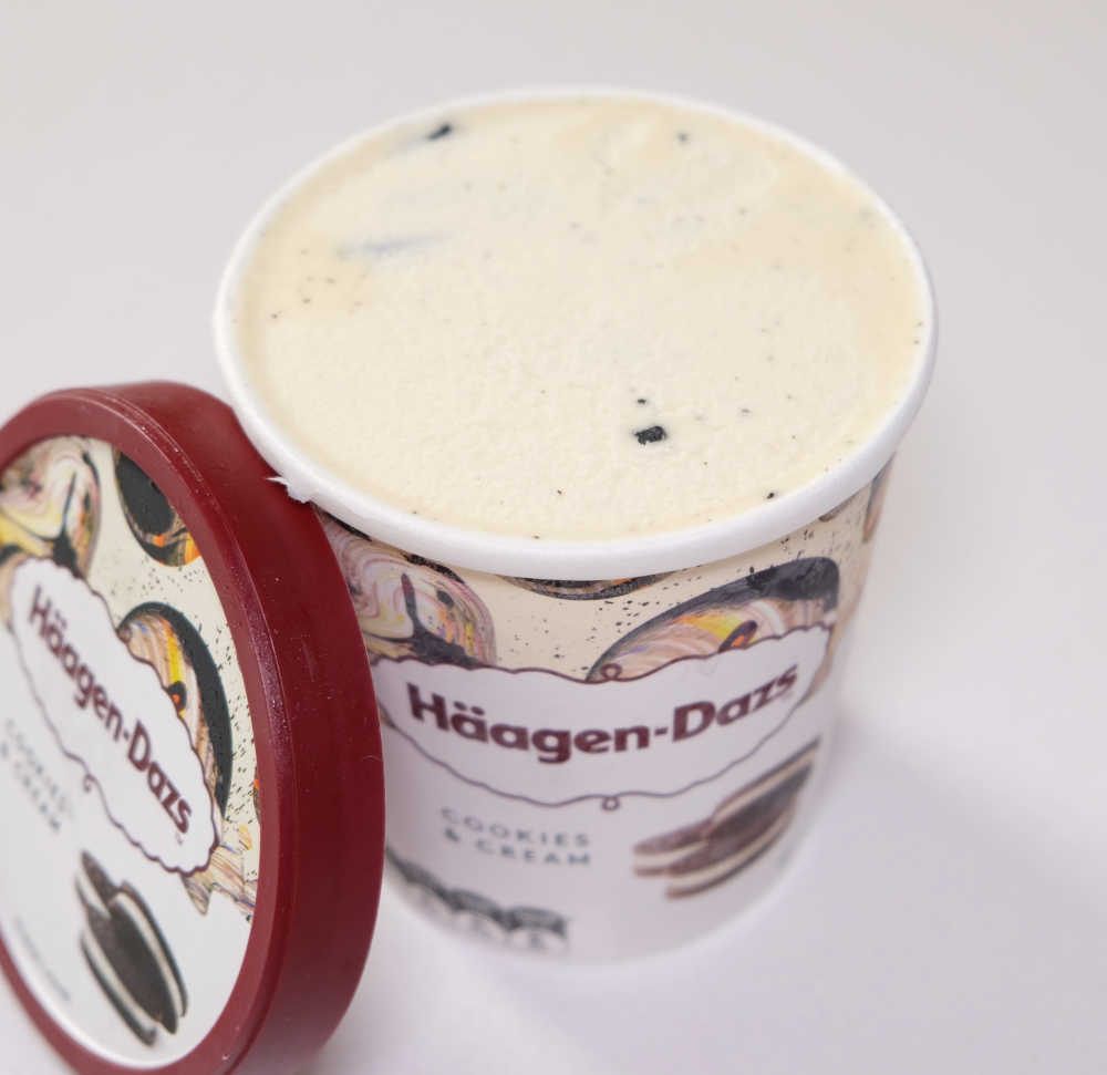 An angled top-down shot of a tub of opened unscooped Haagen-Dazs Cookies and Cream Ice Cream.