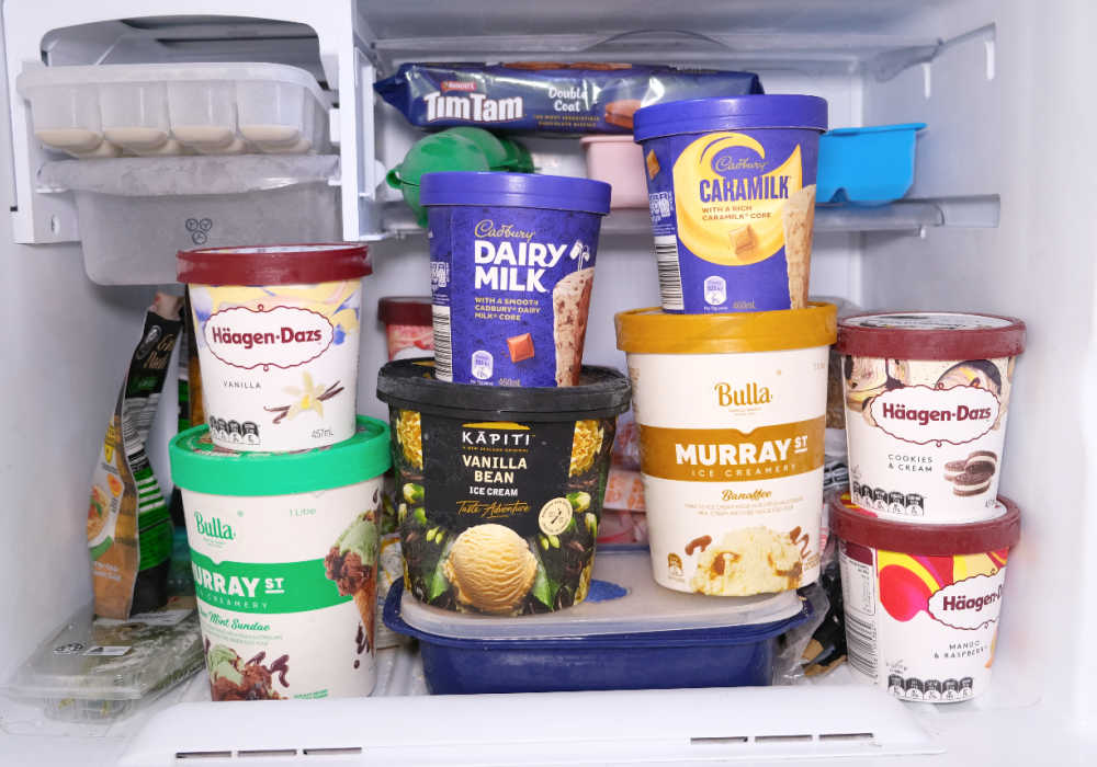 A selection of different ice cream tubs in a freezer.