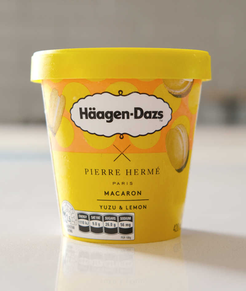 A portrait photo of a container of macaron yuzu lemon ice cream on a benchtop.