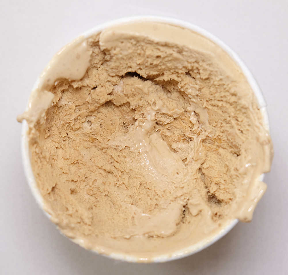 Top-down shot of a partly eaten container of Woolworths Cafe Latte and Biscuits Ice Cream.