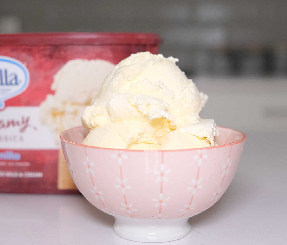 A bowl filled with Bulla Creamy Classics Vanilla Ice Cream with pack in the background.