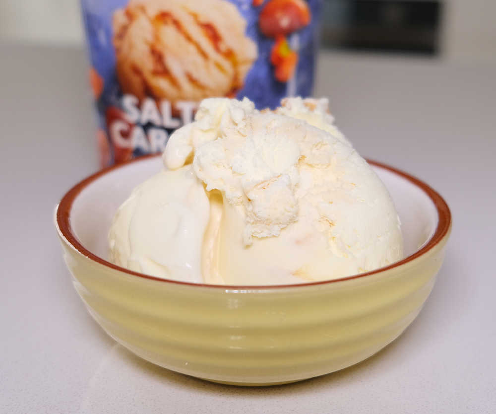 A bowl of Salted Caramel Ice Cream in a yellow bowl with the Coles container in the background.
