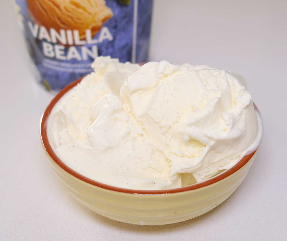 A bowl of Coles Vanilla Bean Ice Cream with the tub in the background.
