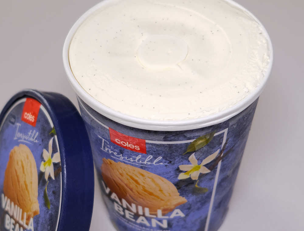 An opened pack of Coles Vanilla Bean Ice Cream with the lid resting on the side.