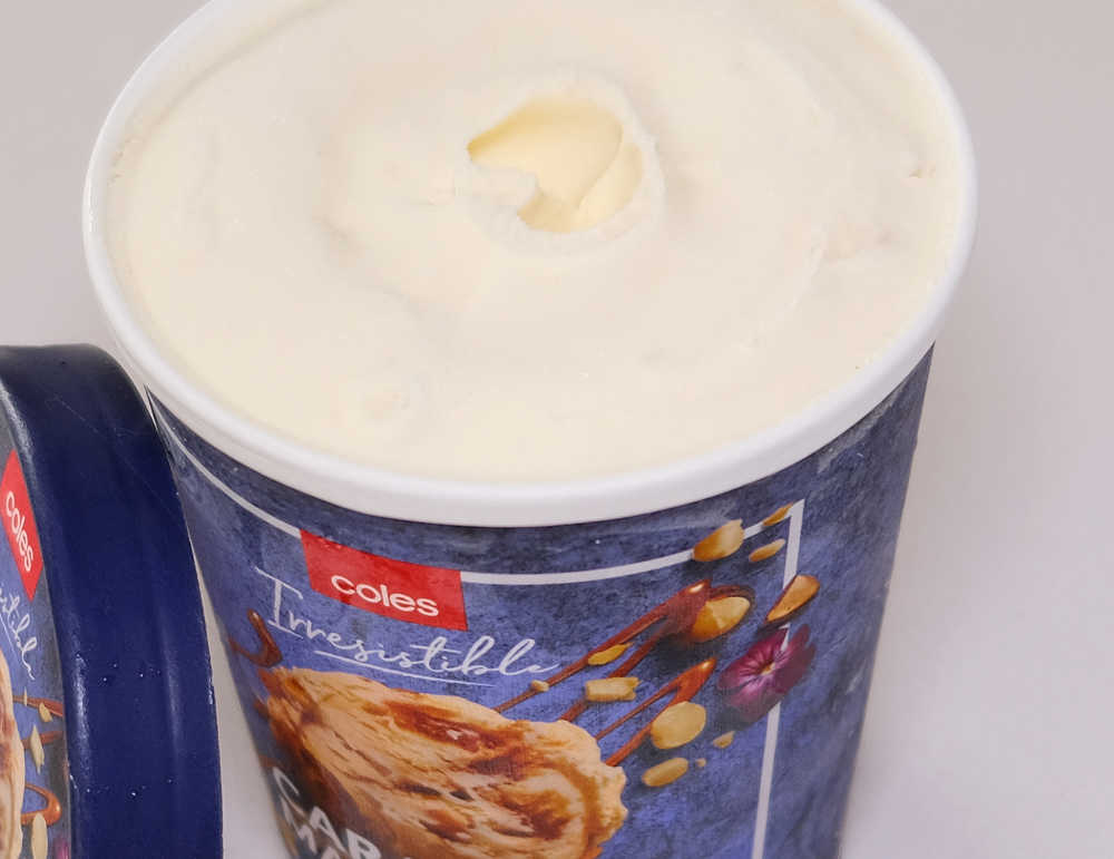 An open pack of Coles Caramel & Macadamia with the lid leaning against the side.