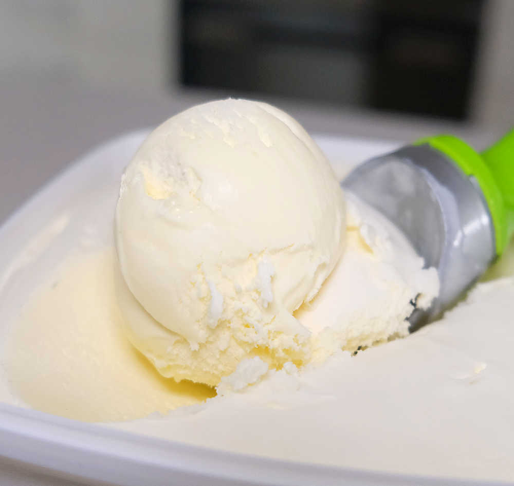 Closeup of an ice cream scoop with Woolworths Vanilla RF Ice Cream.