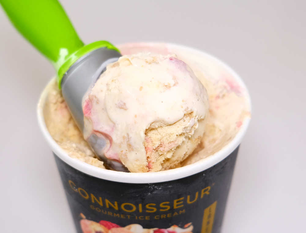 A scoop of Jam Doughnut Ice Cream resting on the tub.
