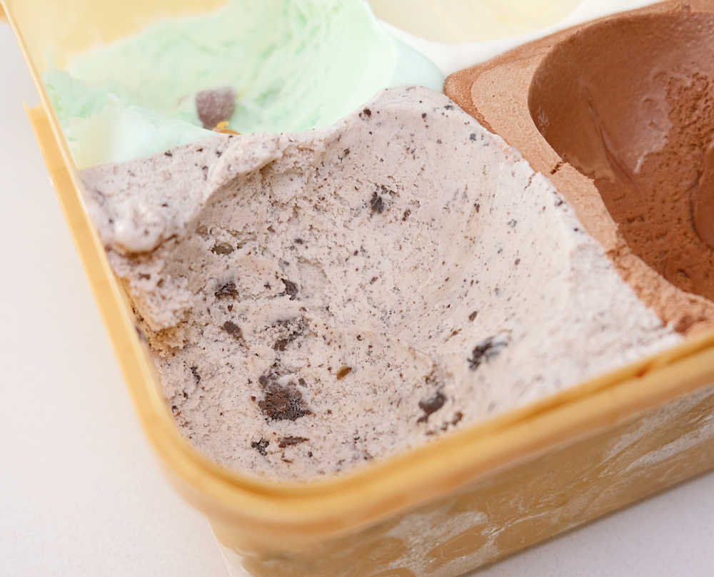A zoomed in photo of Much Moore Family Classic Ice Cream tub showing the vanilla with cookie pieces flavour.