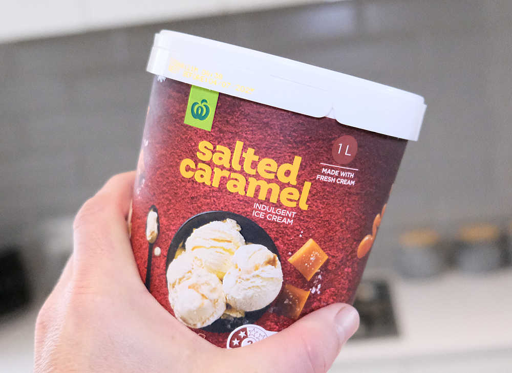 A hand holding a pack of WOW caramel ice cream.