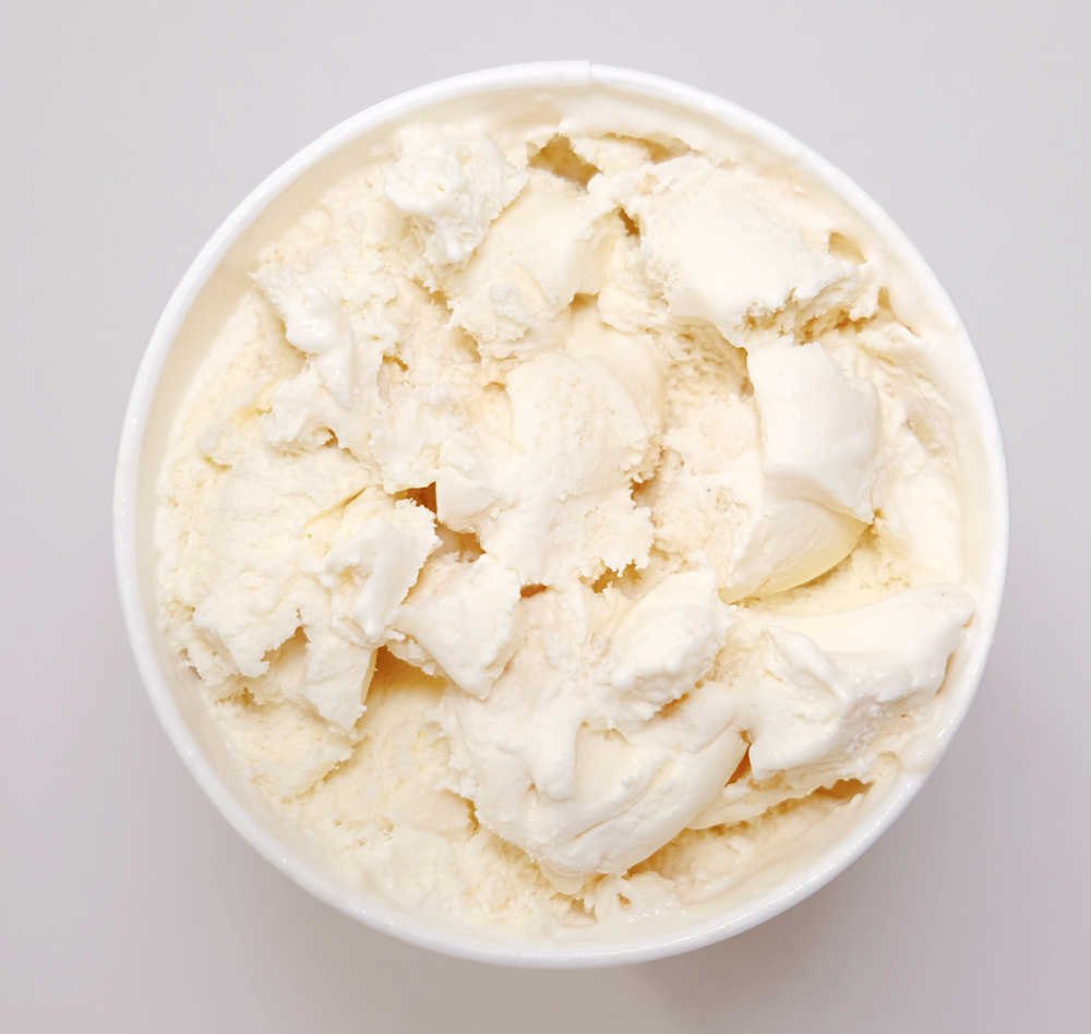 A partly eaten container of Coles Caramel and Macadamia ice cream.