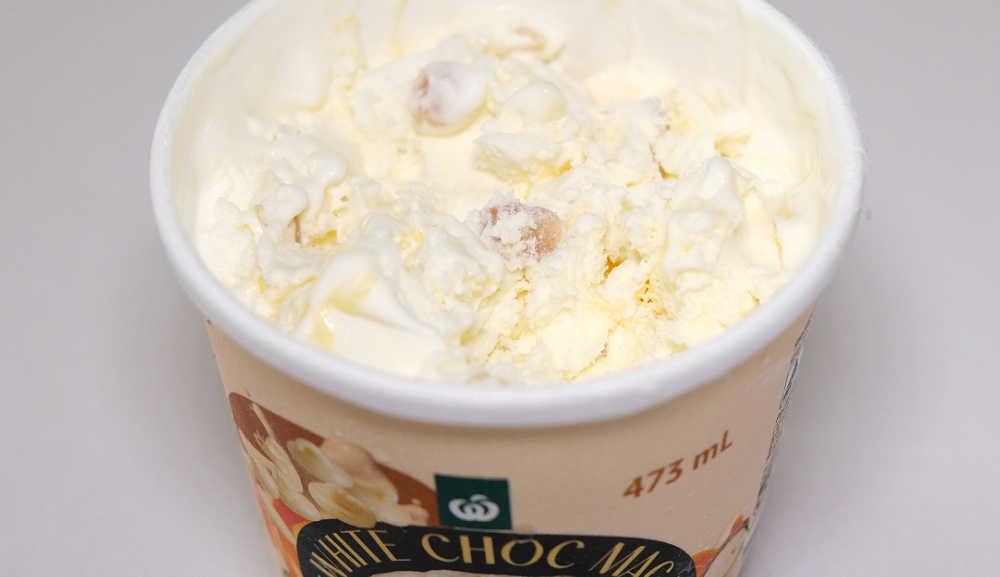 A partly eaten container of Woolworths White Choc Maca Mango Ripple.
