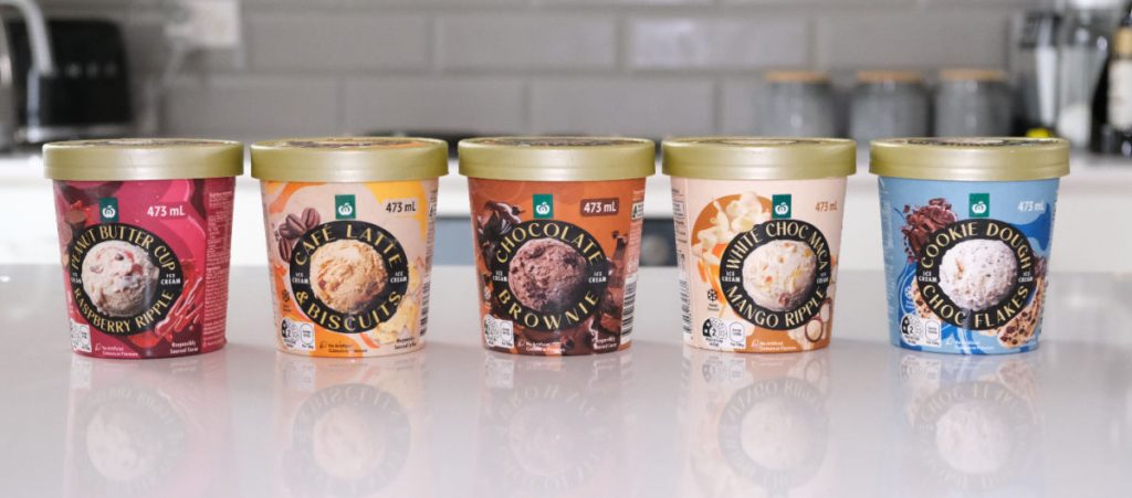 A line of Woolworths ice cream pints on a kitchen countertop.