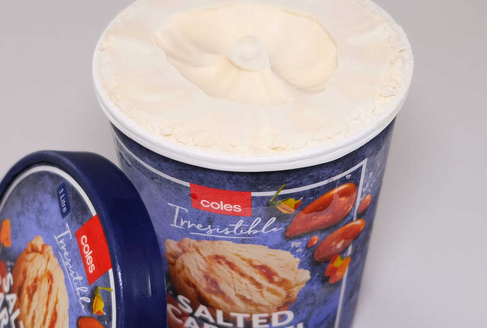 An opened pack of Coles Salted Caramel Ice Cream with the lid leaning against the side.