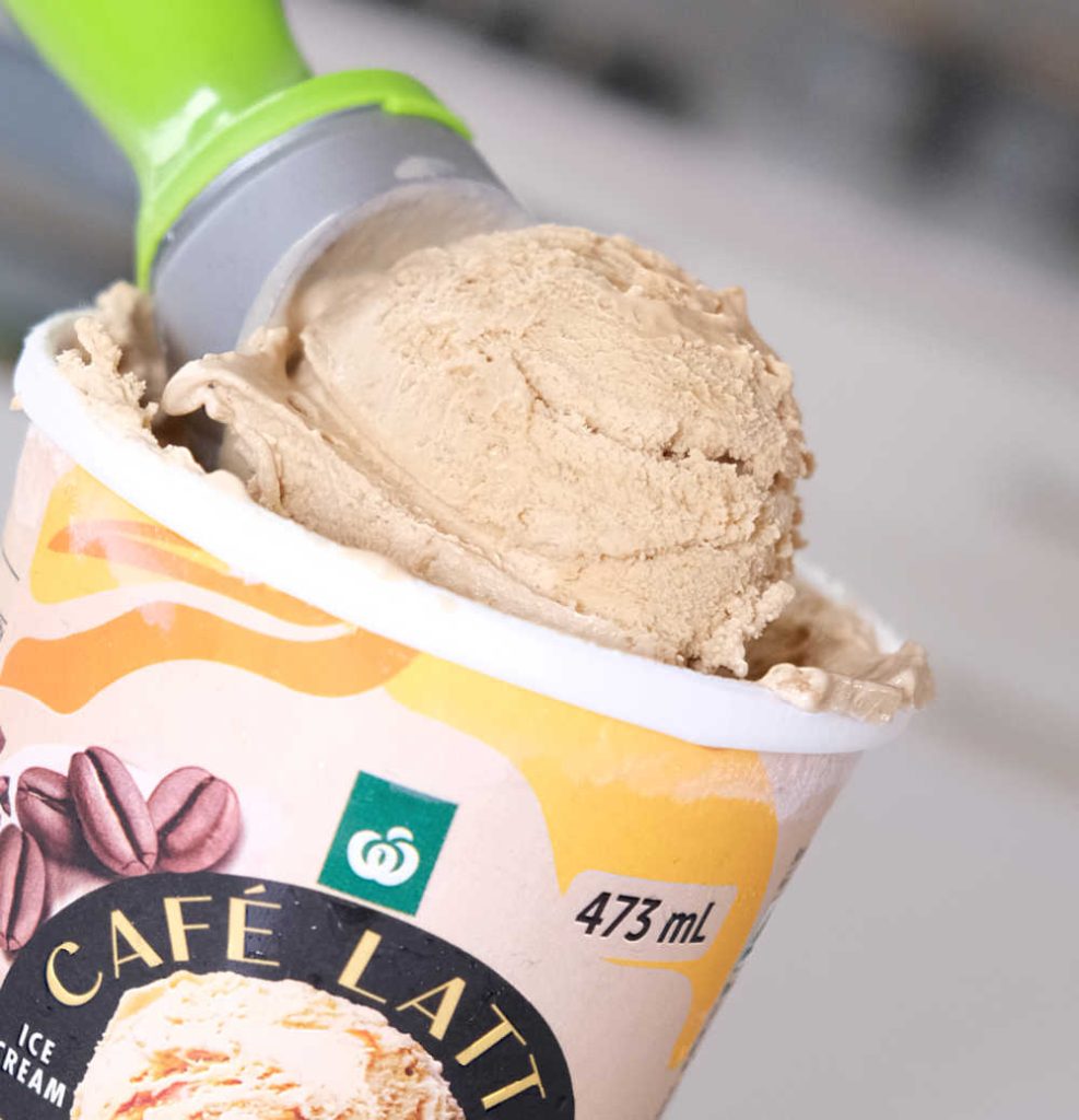 Closeup of a scoop of Woolworths Cafe Latte & Biscuits Ice Cream resting on the tub.