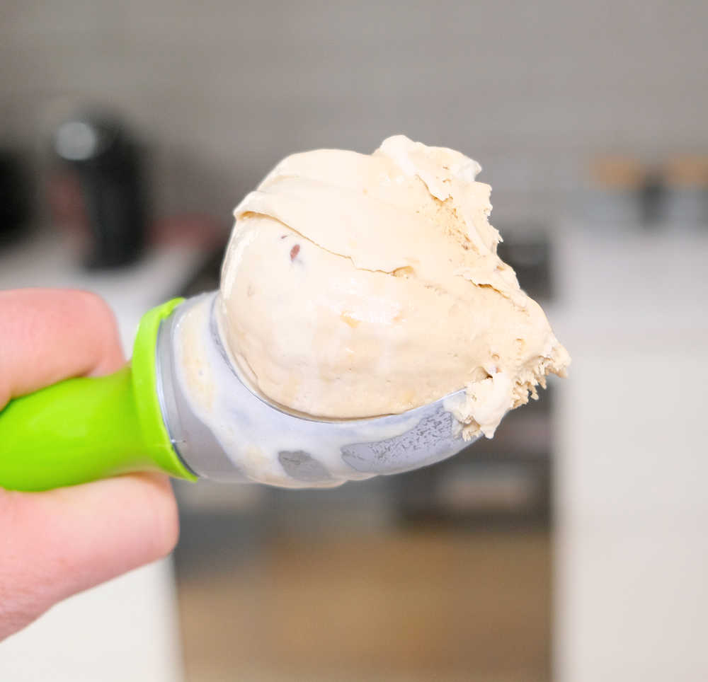 Closeup of a scoop of peanut butter ice cream with a blurred kitchen in the background.