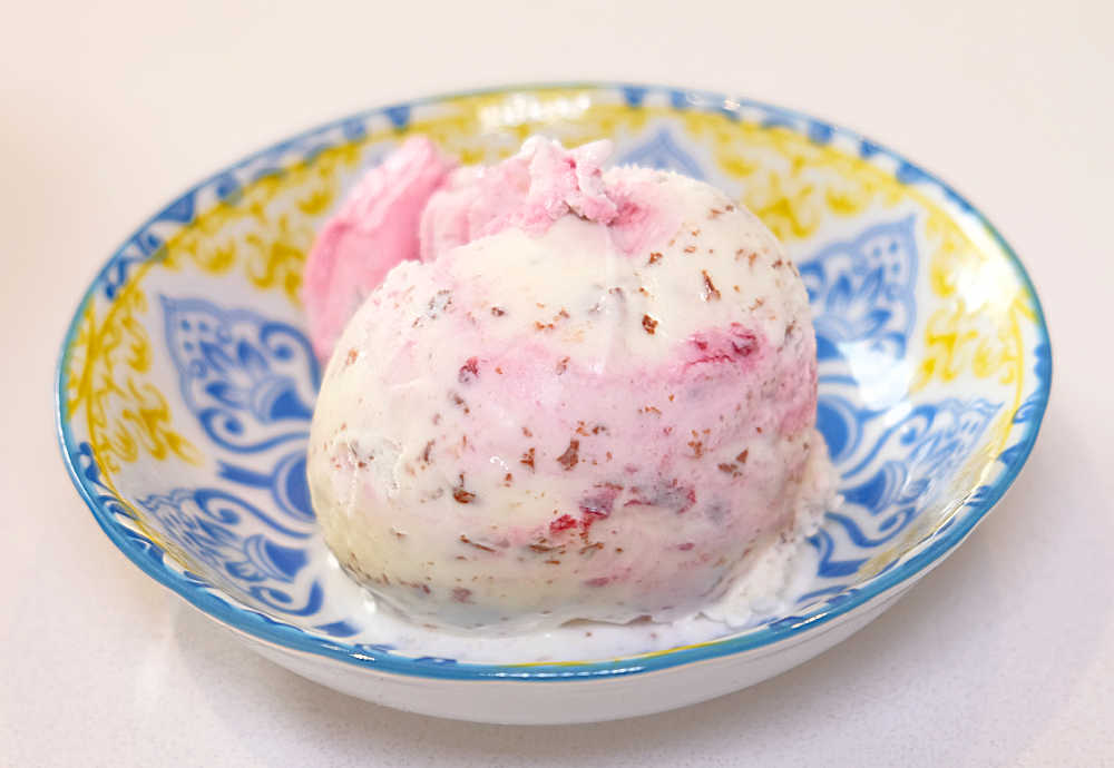 A colourful bowl with a ball of Awesome Boysenberry Stracciatella ice cream.