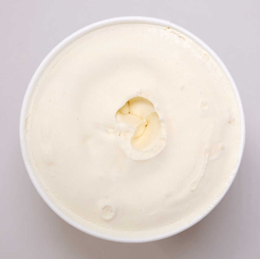Top-down photo of an unscooped, open tub of Coles Irresistible Caramel and Macadamia ice cream.