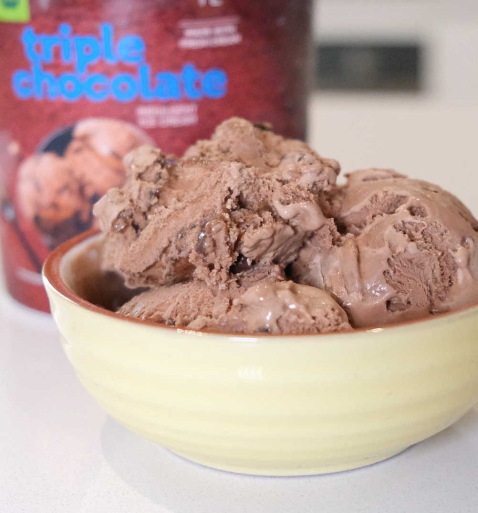 A bowl of WOW Triple Chocolate Ice Cream with the container in the background.