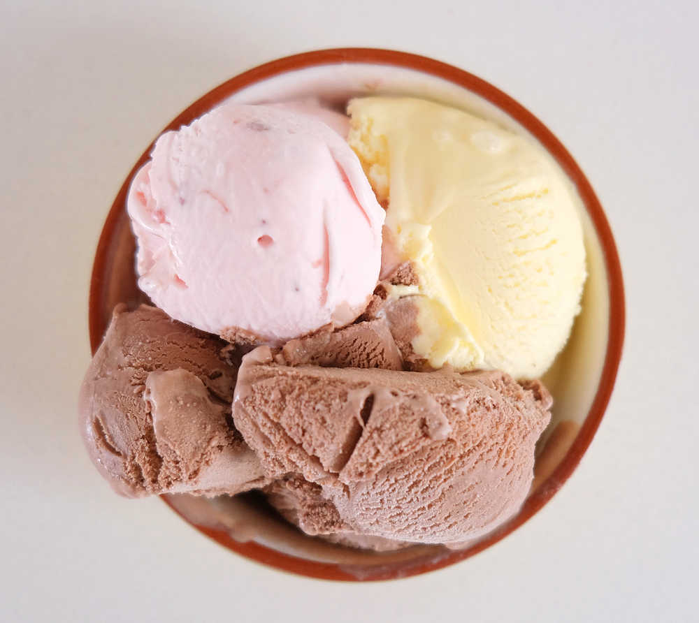 Top down view of a bowl filled with Bulla Creamy Classics Neapolitan Ice Cream. There is a scoop of chocolate, vanilla, and strawberry.