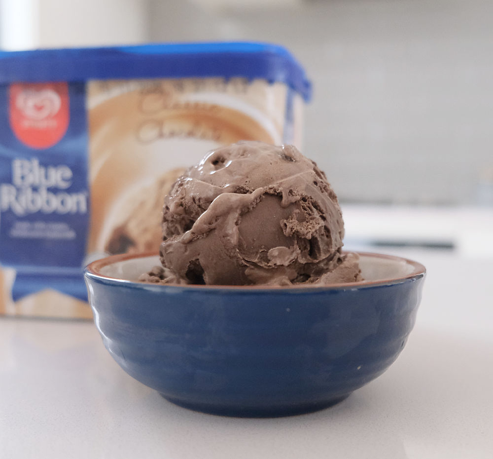 A bowl of chocolate ice cream by Blue Ribbon with the pack in the background.