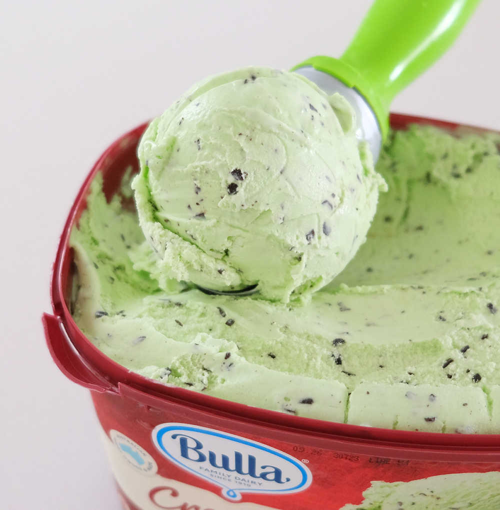A closeup image of a scoop of mint chocolate chip ice cream lying on the Creamy Classics tub.