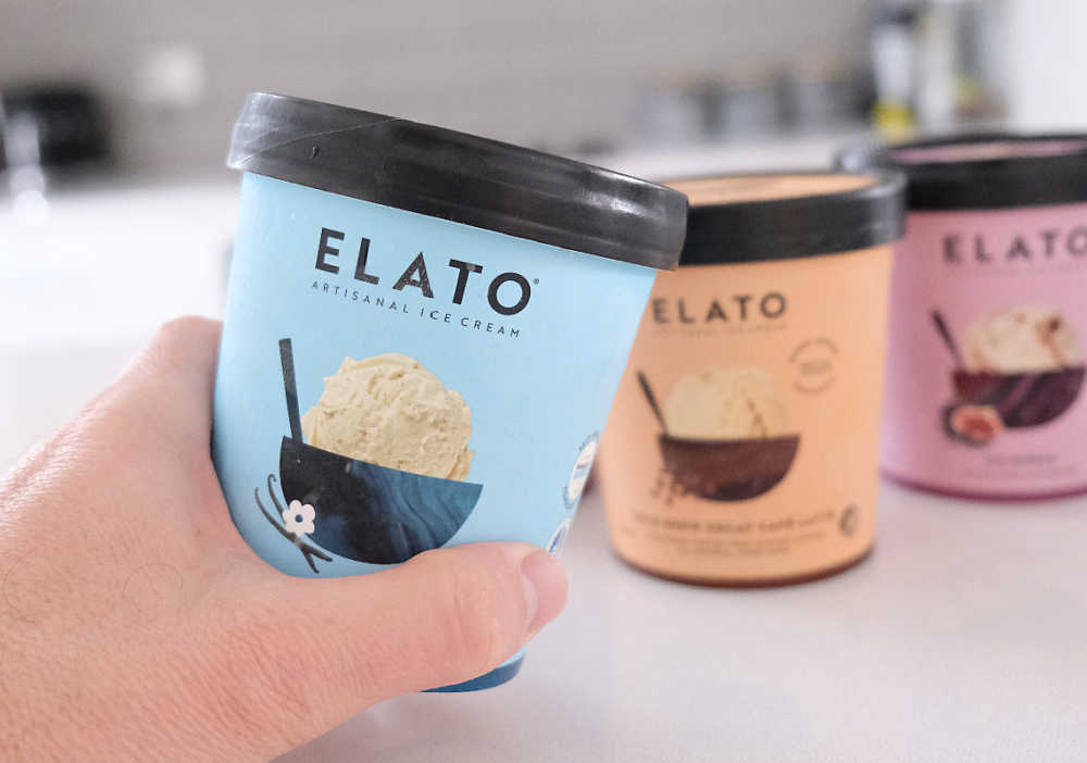 Holding a tub of Elato Triple Vanilla Ice Cream with the rest of the range in the background.