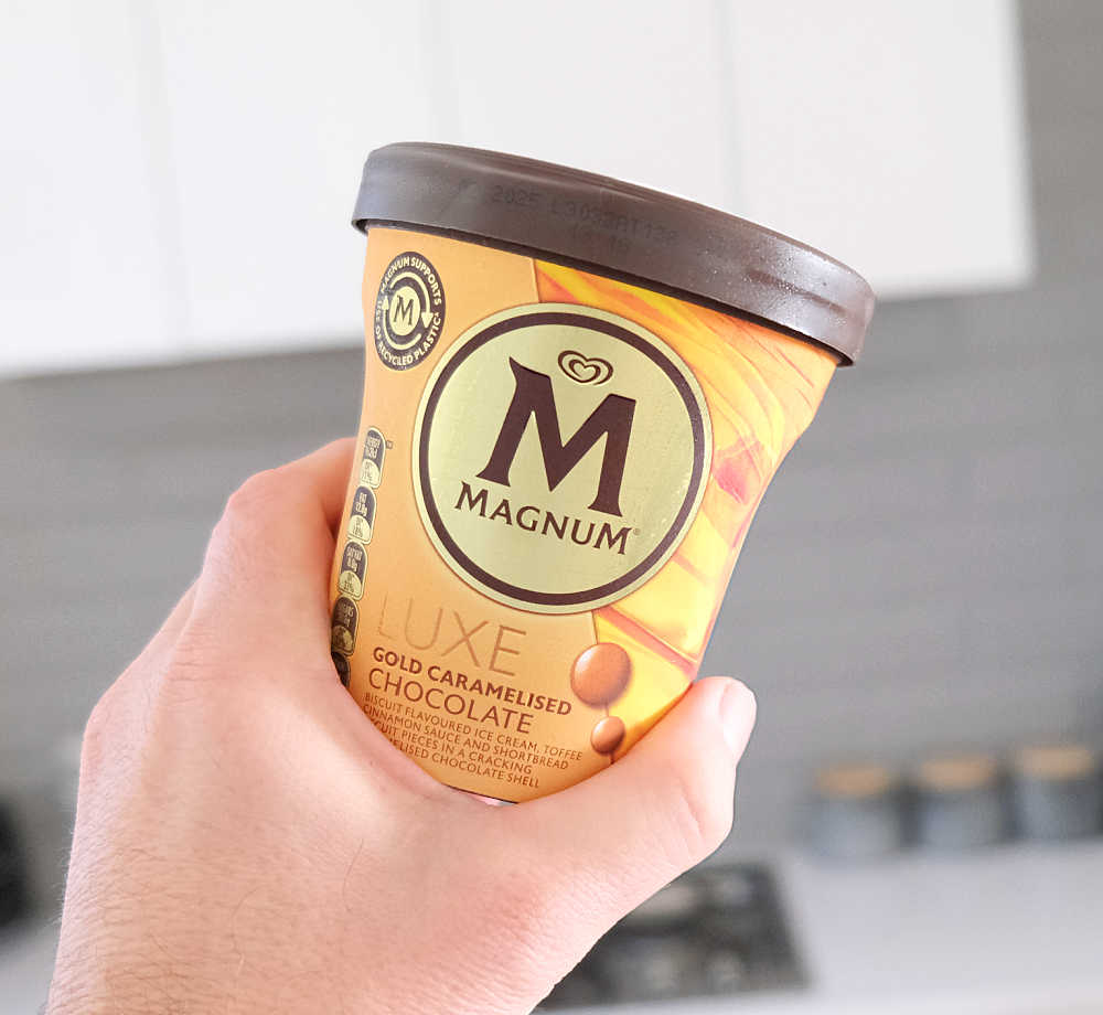 Holding a container of Luxe Gold Caramelised Chocolate ice cream.