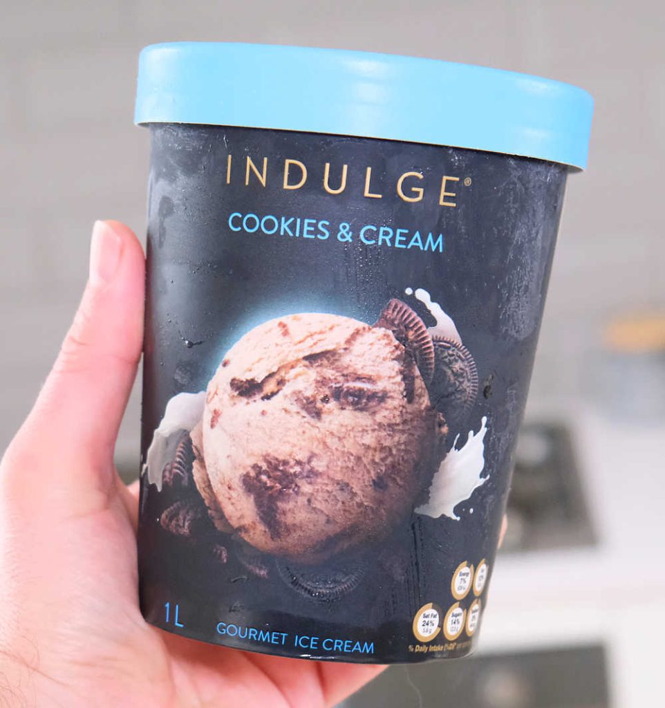 Holding a tub of Indulge Cookies and Cream Ice Cream.