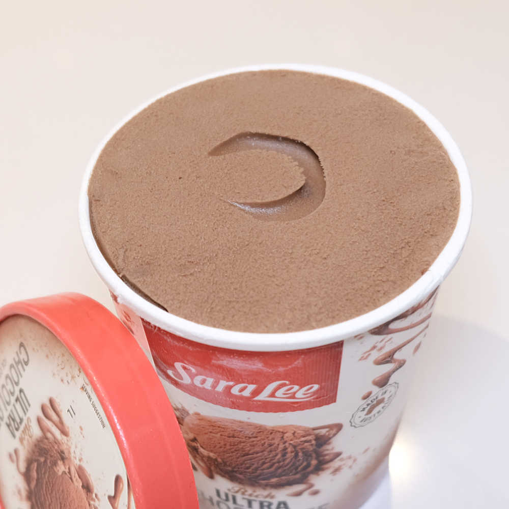 An unscooped tub of Sara Lee Ultra Chocolate 1L with the lid leaning against the side.