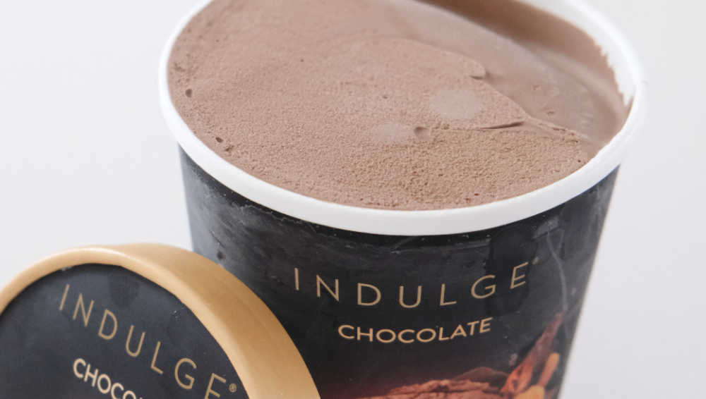 An unscooped container of Indulge Chocolate Frozen Dessert with the lid leaning against the side of the pack,
