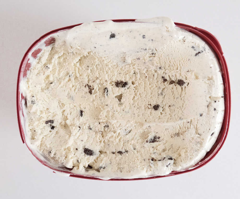 A top down container of partly eaten container of cookies and cream ice cream by Bulla.
