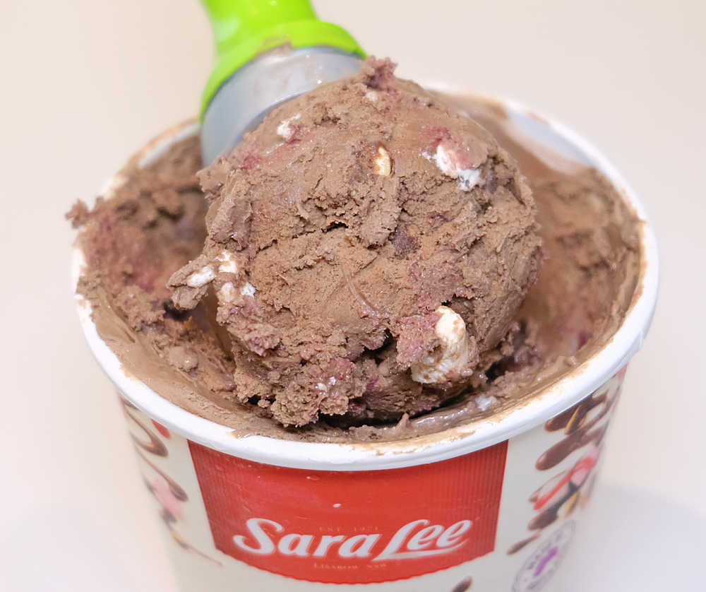 Closeup of a scoop of Rocky Road Ice Cream resting on the top of the container.